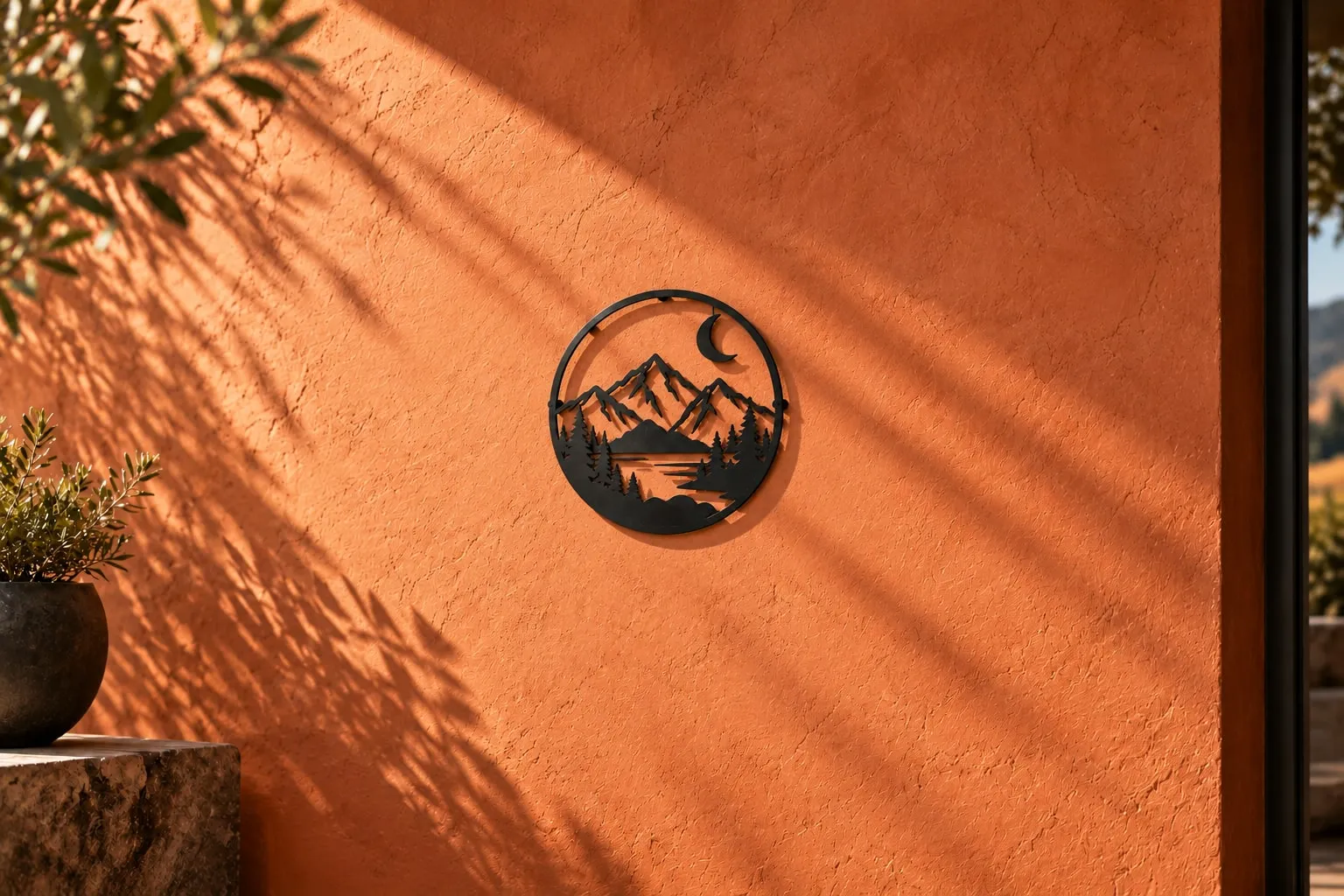 Black steel mountain and moon cut-out sign mounted on terracotta plaster