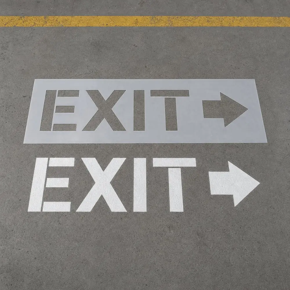 Reusable Mylar EXIT stencil beside a finished warehouse floor marking