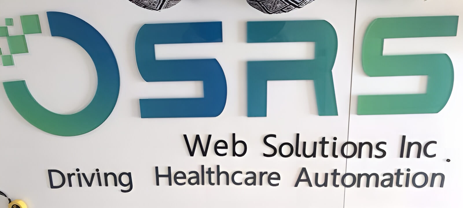 Blue-to-green gradient letters spelling "OSRS" above black text reading "Web Solutions Inc" and "Driving Healthcare Automation", on a white wall