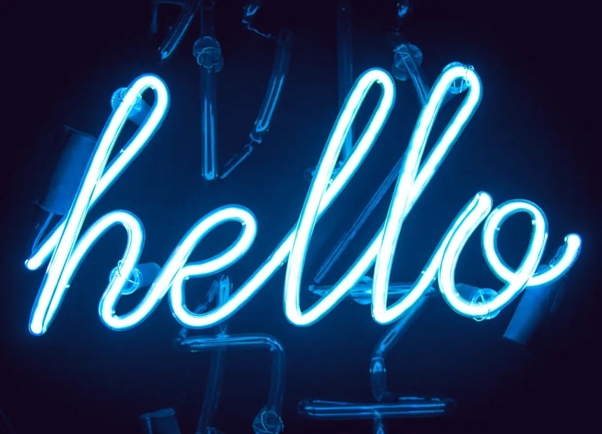 Animated image of the word "hello" in cursive neon tube on a black background, switching between electric blue, pale pink and red-orange glows